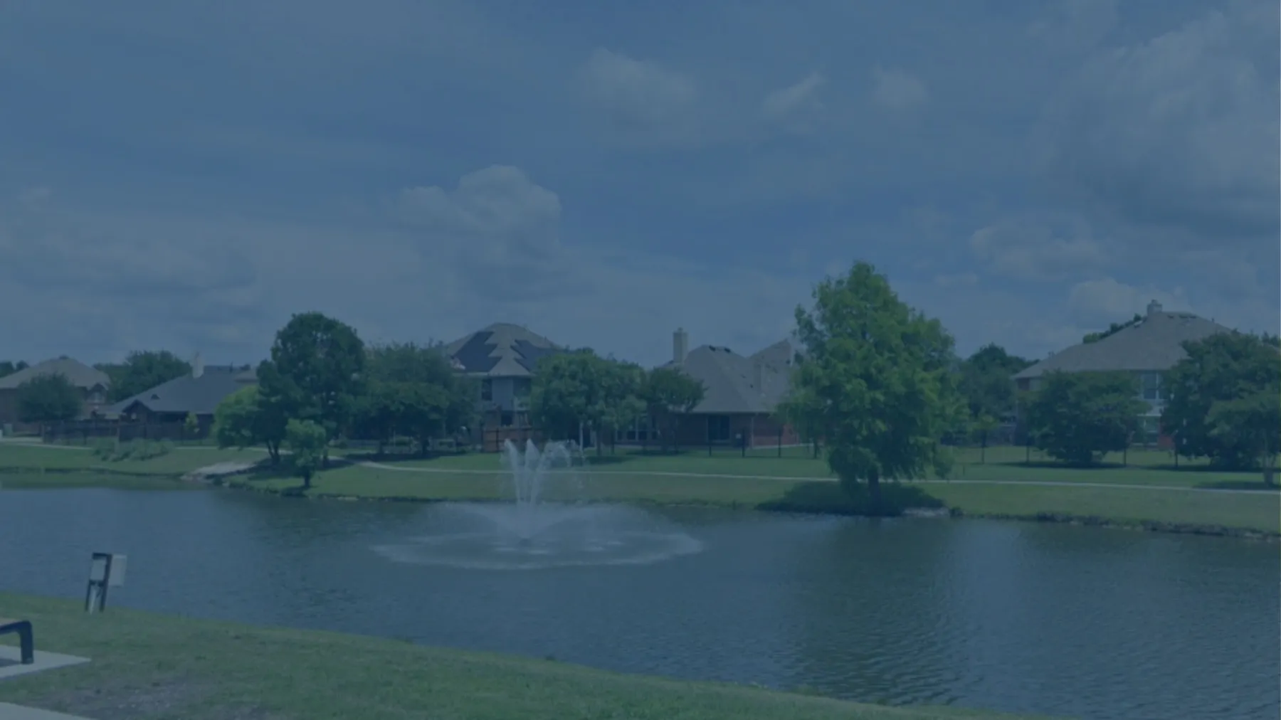 A neighbourhood pond with a fountain and homes behind it in Allen, Texas