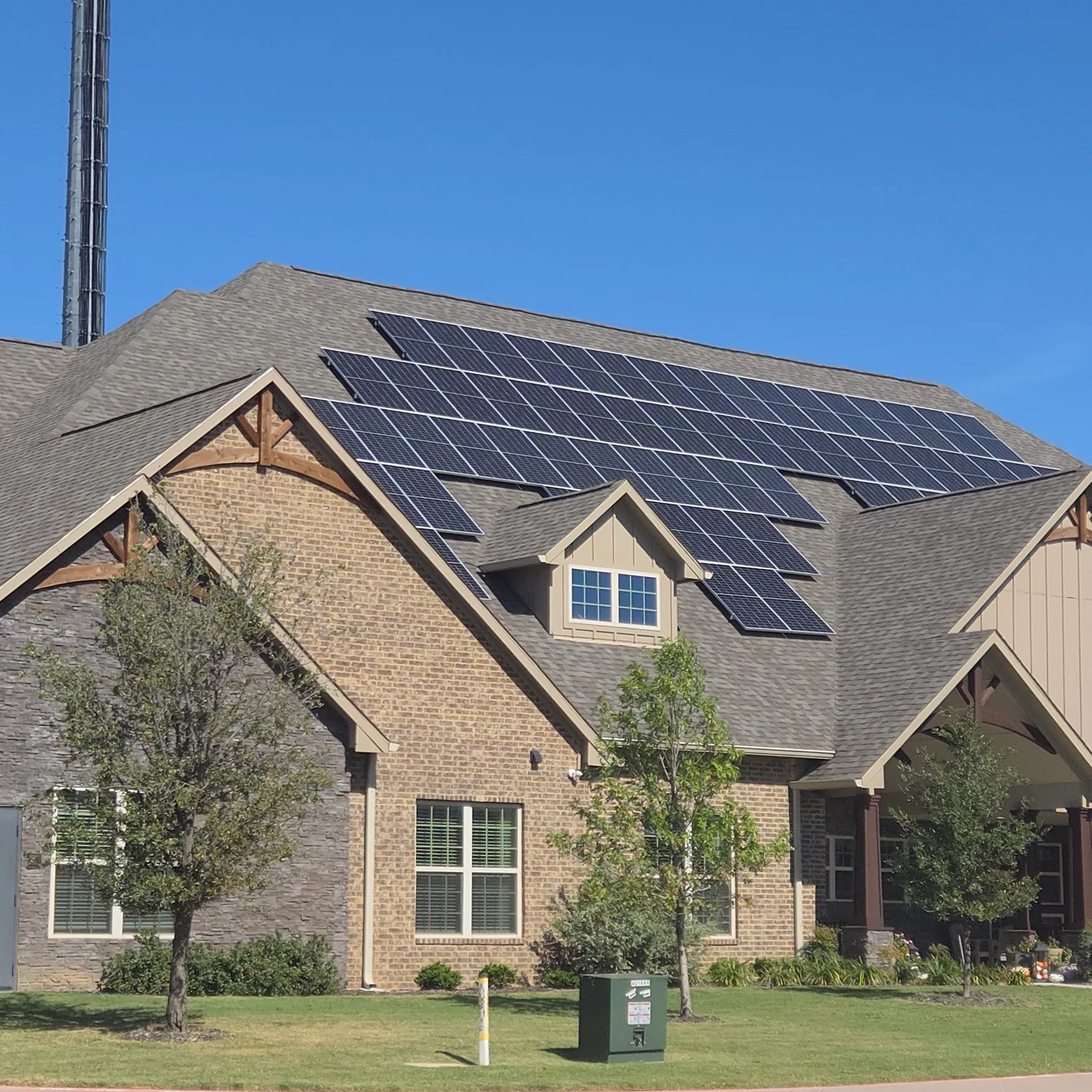 A North Texas brick home with a large rooftop solar array under a clear blue sky