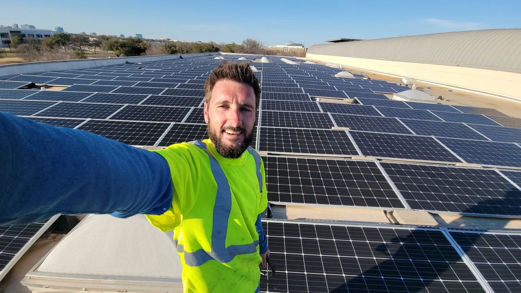 Michael, owner of Power Up Solar Cleaning, in a high-visibility shirt on a commercial rooftop solar array